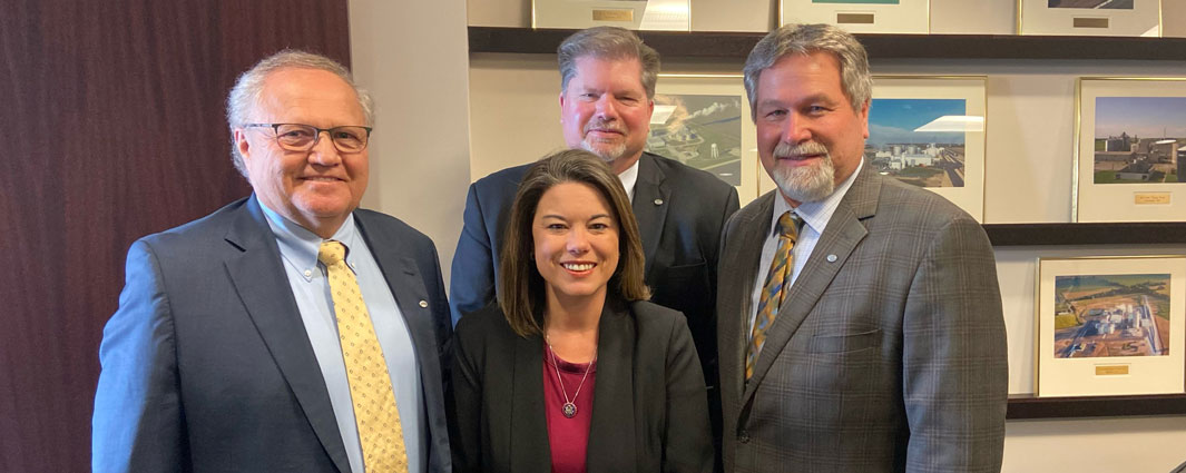 three men and one woman wearing suits